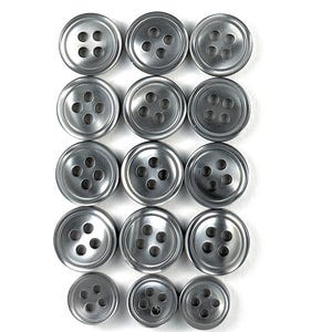 May include: A collection of silver-colored buttons arranged in rows. Each button has four holes and a slightly concave surface. The buttons vary in size, with the smallest at the bottom and the largest at the top. The buttons are made of metal.