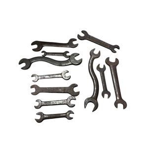 May include: A collection of ten dark grey metal open-ended spanners of varying sizes and shapes. The set includes several straight double-ended spanners and two curved spanners, all showing signs of wear and oxidation on their surfaces.