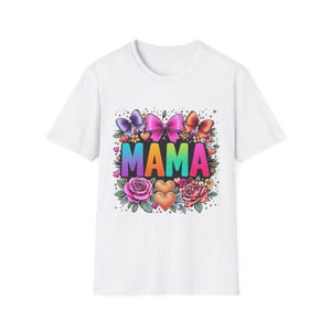 May include: White t-shirt featuring the word "MAMA" in rainbow colours. The design includes bows, hearts, and flowers in pink, purple, orange, and green. A colourful and cheerful design.