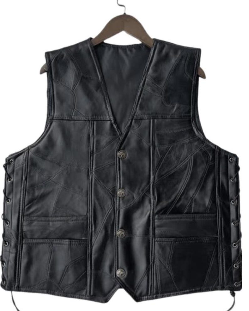 K&ouml;nnte beinhalten: Schwarze Lederweste mit V-Ausschnitt und vier dekorativen Kn&ouml;pfen. Die Weste hat zwei Vordertaschen und seitliche Schn&uuml;rungen. Das Leder ist in einem Patchwork-Design gen&auml;ht. Die Weste h&auml;ngt an einem Holzb&uuml;gel.