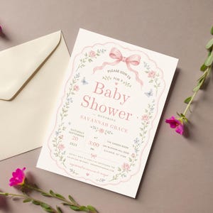 May include: A cream-colored baby shower invitation card featuring a pink scalloped border, a pink ribbon bow, and floral illustrations. The text reads: Please join us for a Baby Shower honoring Savannah Grace, September 20, 2025, at 3:00 PM.