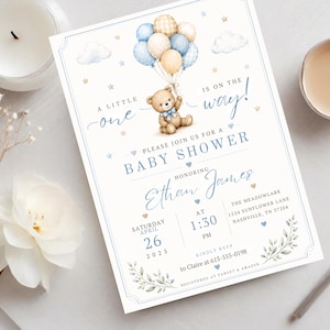May include: A baby shower invitation card featuring a brown teddy bear holding a cluster of blue, cream, and checkered balloons. The text reads: A little one is on the way! Please join us for a baby shower honoring Ethan James on Saturday, April 26, 2025, at 1:30 PM.