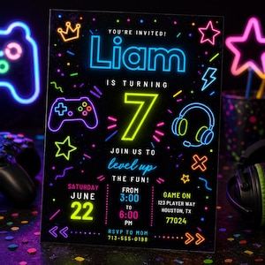 May include: A black rectangular birthday invitation card featuring neon-style graphics of a game controller, headphones, stars, and a crown. The text reads: YOU'RE INVITED! Liam IS TURNING 7 JOIN US TO level up THE FUN! SATURDAY JUNE 22 FROM 3:00 TO 6:00 PM.