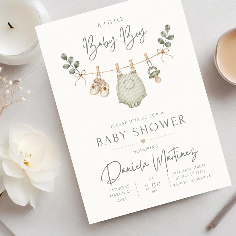 Puede incluir: Una tarjeta de invitaci&oacute;n blanca para baby shower con ilustraciones en acuarela de zapatos de beb&eacute;, un mameluco y un chupete colgados de una cuerda con hojas de eucalipto. El texto dice A LITTLE Baby Boy y PLEASE JOIN US FOR A BABY SHOWER.