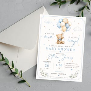 May include: A white baby shower invitation card featuring a watercolor illustration of a teddy bear holding blue, tan, and plaid balloons. The text reads A LITTLE one IS ON THE WAY! BABY SHOWER, Ethan James, Saturday April 26 2025, 1:30 PM, and registry info.