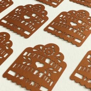 Puede incluir: Primer plano de varias etiquetas de papel marr&oacute;n recortadas con intrincados dise&ntilde;os florales y de coraz&oacute;n. Cada etiqueta tiene las palabras "THANK YOU" recortadas. Las etiquetas tienen un borde festoneado y est&aacute;n dispuestas sobre una superficie blanca.