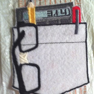 May include: A white felt patch with a black outline depicting a pocket with a pencil, a cassette tape, and glasses inside. The cassette tape has the text "3.14" on it.