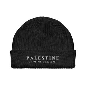 Könnte beinhalten: Schwarze Strickmütze mit dem Wort "PALESTINE" und den Koordinaten "31.7761° N 35.2358° E" in weiß gestickt.