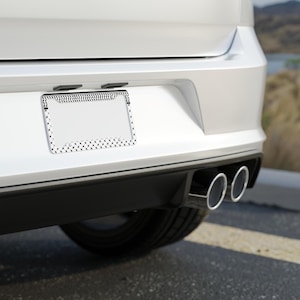 Könnte beinhalten: Ein weißes Auto mit einem schwarzen Kennzeichenrahmen und zwei Auspuffrohren.