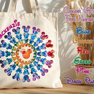 May include: A white canvas tote bag with a colorful tie-dye design featuring a circle of Mickey Mouse heads. The name "MACKENZIE" is written in pink letters on the bag. The text "COLOR OPTIONS FOR NAME" is written in pink letters on a white background. The text "BLUE", "ORANGE", "RED", "GREEN", "PINK", and "DARK PURPLE" is written in various colors on a white background.
