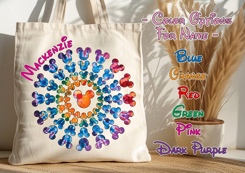 May include: A white canvas tote bag with a colorful tie-dye design featuring a circle of Mickey Mouse heads. The name "MACKENZIE" is written in pink letters on the bag. The text "COLOR OPTIONS FOR NAME" is written in pink letters on a white background. The text "BLUE", "ORANGE", "RED", "GREEN", "PINK", and "DARK PURPLE" is written in various colors on a white background.
