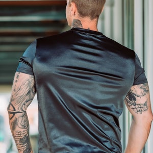 May include: Black satin t-shirt and shorts set. The short-sleeved top has a crew neck and the shorts have a comfortable fit. The fabric has a shiny, smooth texture. The model has tattoos on both arms.