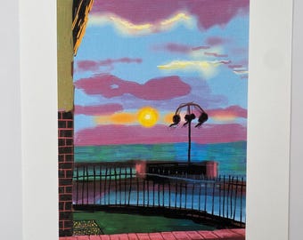 May include: A print featuring a vibrant sunset with purple and blue clouds over a dark sea. A black metal fence borders a green lawn in the foreground, while a single street lamp stands near the water. The print includes a signature and edition number.