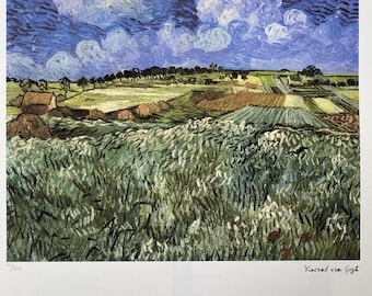 May include: A framed print of a landscape painting by Vincent van Gogh. The artwork depicts a field of wheat in shades of green and yellow, under a blue sky with white, swirling clouds. The artist's signature is visible in the bottom right corner.