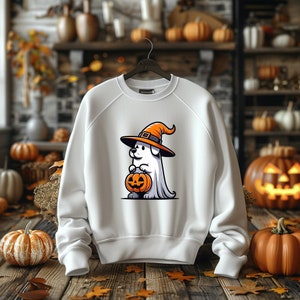 Puede incluir: Sudadera blanca con un gr&aacute;fico de un perro fantasma que lleva un sombrero de bruja y sostiene una calabaza de Halloween. El perro lleva un sombrero de bruja con un borde naranja y una parte superior negra. El perro sostiene una calabaza de Halloween con una cara tallada. La sudadera es blanca con cuello redondo y mangas largas.