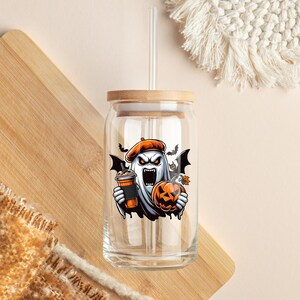 May include: A clear glass jar with a bamboo lid and a straw. The jar has a Halloween-themed sticker of a ghost holding a pumpkin and a cup of coffee.
