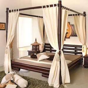 Puede incluir: Una cama con dosel marrón oscuro con cortinas color crema y cojines decorativos. Dos mesitas de noche a juego con lámparas flanquean la cama. La cama está sobre una alfombra verde.