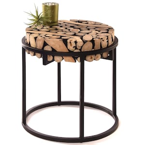 Könnte beinhalten: Ein runder Beistelltisch mit einer einzigartigen Tischplatte aus Holzstücken. Der Tisch hat ein schwarzes Metallgestell mit rundem Sockel und vier Beinen. Eine kleine grüne Pflanze und ein goldfarbener Kerzenhalter stehen darauf.