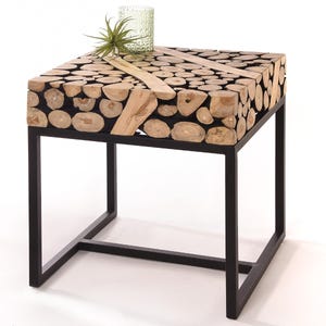 Könnte beinhalten: Quadratischer Beistelltisch aus Holz mit schwarzem Metallrahmen. Die Tischplatte besteht aus kleinen, hellfarbigen Holzstücken, die in einem Mosaikmuster angeordnet sind. Eine kleine grüne Pflanze und eine strukturierte Glasvase stehen darauf. Der Tisch ist etwa 51 cm groß.