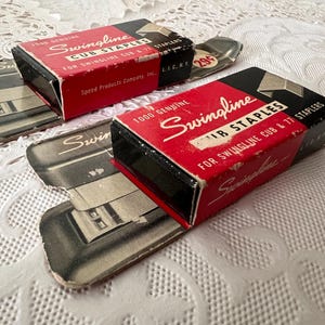May include: Two vintage Swingline Cub Staples boxes with red and black packaging. The boxes are labeled "1000 Genuine Cub Staples" and "For Swingline Cub & 77 Staplers". The boxes sit on top of vintage stapler packaging.