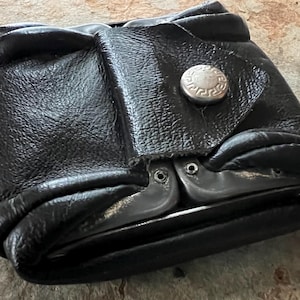 May include: A white ceramic mug with a black handle and the text "But First, Coffee" in a black, bold font. The mug is sitting on a wooden surface. The mug is approximately 4 inches tall.