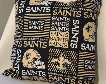 Könnte beinhalten: Ein schwarzes und goldenes Kissen mit einem Saints-Logo und dem Wort "Saints", das sich über das gesamte Design wiederholt.