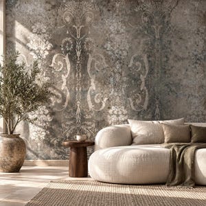 Op de afbeelding: Een muurschildering met een verweerde textuur en een vervaagd, sierlijk damastpatroon in grijze, bruine en beige tinten. Het ontwerp bevat ingewikkelde krulwerk- en bloemmotieven die over een gevlekte, verouderde achtergrond zijn geplaatst.