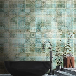 Puede incluir: Una bañera negra se encuentra frente a una pared con un papel tapiz estampado en azul y verde. El papel tapiz tiene un diseño de patchwork con varias formas geométricas y patrones. Un grifo plateado está montado en la pared sobre la bañera. Una planta verde en maceta se encuentra en la esquina de la habitación.