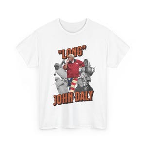 May include: White t-shirt with a graphic of golfer John Daly in a red, white, and blue outfit. The text "LONG" and "JOHN DALY" are printed in orange on the shirt.