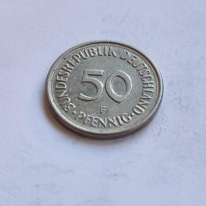 Puede incluir: Una moneda alemana de 50 Pfennig de plata con el texto "Bundesrepublik Deutschland" y "50 Pfennig" alrededor del borde.
