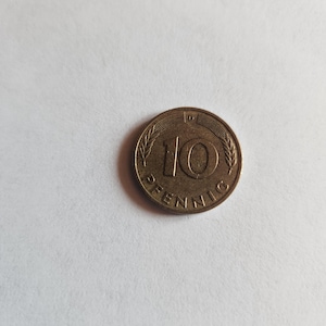May include: A bronze 10 Pfennig coin. The coin displays the number "10" prominently, with the word "PFENNIG" below. The coin is encircled by a wheat-like pattern.