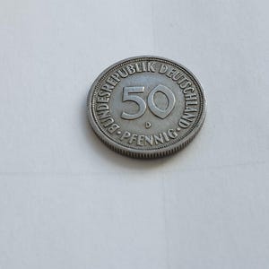 Può includere: Una moneta tedesca da 50 Pfennig d'argento con il testo "Bundesrepublik Deutschland" e "50 Pfennig" attorno al bordo.