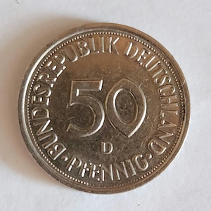 May include: A silver German 50 Pfennig coin with the text "BUNDESREPUBLIK DEUTSCHLAND" and "50 PFENNIG" around the edge.