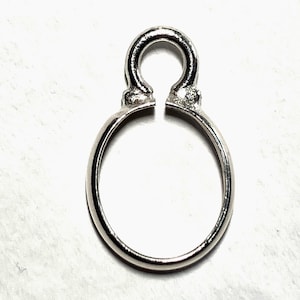 Peut inclure: Un élément de bijouterie argenté avec une boucle ovale et une boucle supérieure arrondie. La boucle supérieure présente un petit espace. L'élément est conçu pour relier deux pièces de bijouterie.