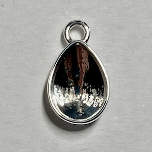 May include: A silver teardrop-shaped pendant with a loop at the top for attaching to a chain or cord.