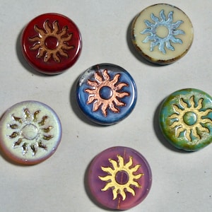 May include: Six round ceramic sun-shaped buttons with gold accents. The buttons are in various colors, including red, blue, green, white, and purple.