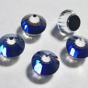 May include: A selection of faceted, round beads. The beads are a deep blue colour with a clear, reflective surface. One bead is clear with a black centre. The beads have a hole drilled through the centre, suggesting they are for jewellery making.