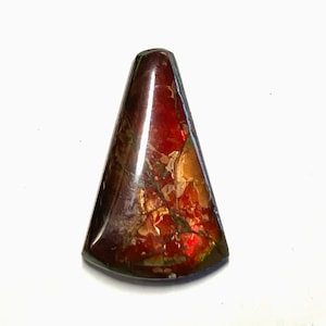 May include: A polished, triangular gemstone with a rich, iridescent color palette. The stone transitions from deep reds and browns to hints of gold and green, showcasing a natural, textured pattern. This unique piece is likely a cabochon.