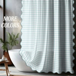 May include: A light blue and white gingham shower curtain with a scalloped edge. The text "MORE COLORS" is displayed on the left side of the curtain. The curtain is hanging in a bathroom with a white bathtub and a plant.