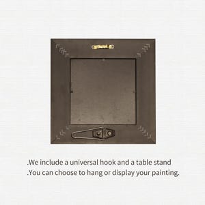 May include: The back of a square, dark brown picture frame with a metal hook and stand. The frame has decorative stitching along the edges. Text at the bottom reads, "We include a universal hook and a table stand. You can choose to hang or display your painting."