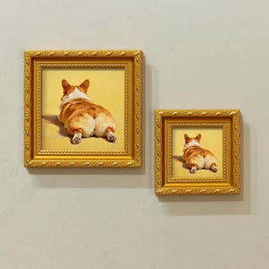 Pu&ograve; includere: Due stampe incorniciate di un cane corgi, visto da dietro, sdraiato. Il cane ha un mantello marrone e bianco ed &egrave; ambientato su uno sfondo giallo. Le cornici sono dorate con dettagli ornati.