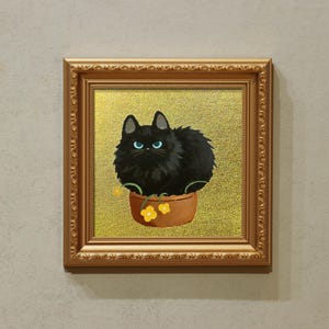 May include: A framed painting featuring a black cat with blue eyes in a brown flower pot with yellow flowers. The artwork has a gold background and is in a gold ornate frame. The painting is displayed on a neutral wall.