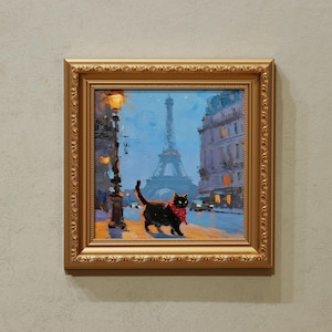 May include: Framed oil painting of a black cat wearing a red scarf, walking on a Parisian street. The Eiffel Tower is in the background, with streetlights and buildings. The frame is gold.