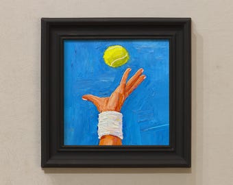 Puede incluir: Pintura al óleo de una mano que alcanza una pelota de tenis. La mano lleva una muñequera blanca. La pelota de tenis es de color amarillo verdoso. El fondo es azul texturizado. La pintura está en un marco negro.