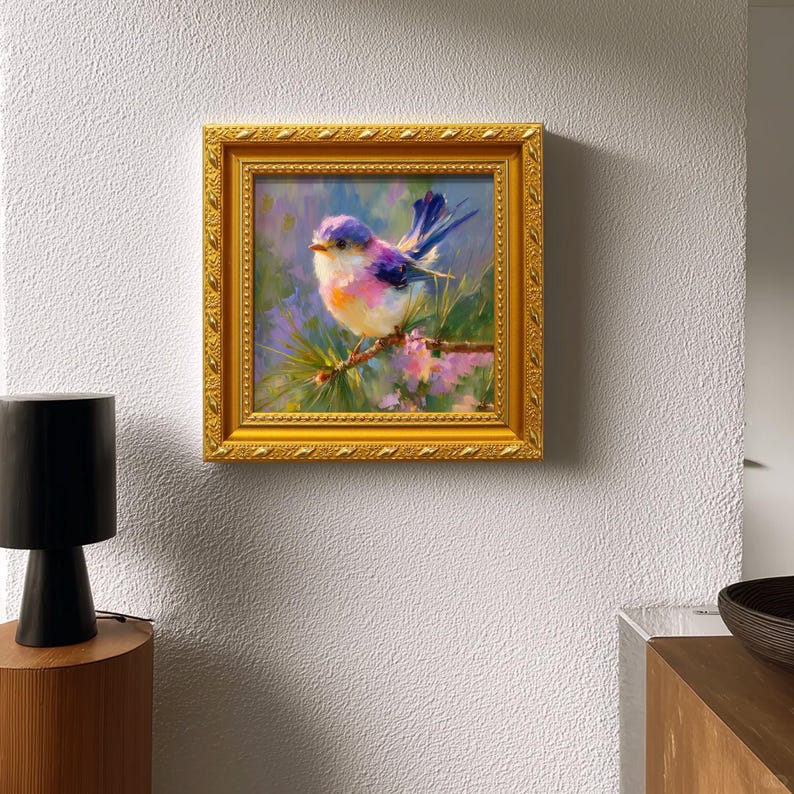 Puede incluir: Pintura enmarcada de un p&aacute;jaro colorido posado en una rama. El p&aacute;jaro tiene plumas azules, moradas y rosas. La pintura est&aacute; en un marco dorado y cuelga de una pared blanca.