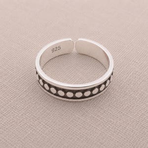 May include: A silver open-band ring featuring a repeating pattern of small, raised circular dots along the center of the outer surface. The interior of the band is clearly stamped with the number 925, indicating the sterling silver composition.