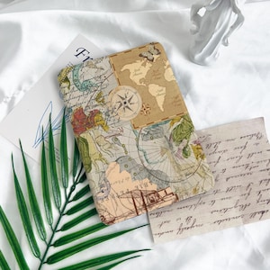 Peut inclure: Une couverture de carnet de style vintage avec une carte du monde, une boussole et d'autres motifs nautiques. La couverture est en papier brun avec un aspect vieilli.