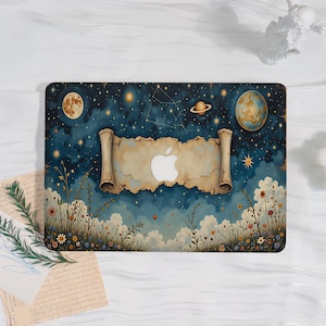 May include: A laptop skin featuring a dark blue night sky with stars, planets, and a moon. A central beige parchment scroll design surrounds a white Apple logo. The bottom section displays a field of colorful wildflowers and green grass.