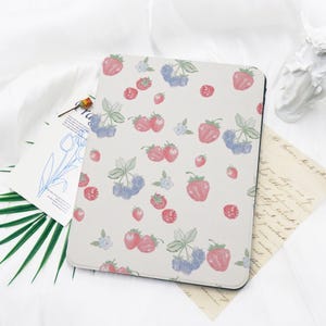 May include: A white tablet case with a repeating pattern of red strawberries, blue raspberries, and smaller red berries with green leaves. The design is a watercolour style, creating a fresh, summery aesthetic.