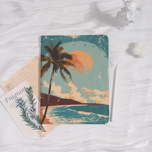 May include: A notebook with a beach scene illustration. The cover depicts a palm tree, ocean waves, and a setting sun in brown, blue, and orange hues. A white stylus is placed next to the notebook. The word "Fragrant" is visible on a card.